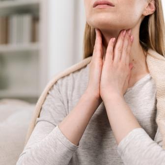 Frau fasst sich an den Hals