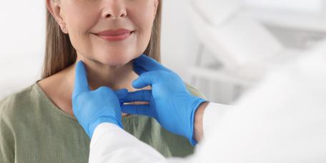 Arzt tastet Hals der Patientin ab